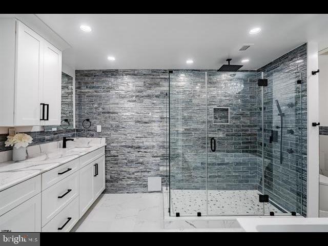 bathroom featuring vanity, tile walls, and walk in shower