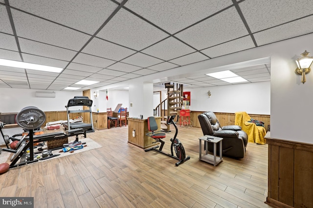 exercise area with a drop ceiling and a wall mounted air conditioner