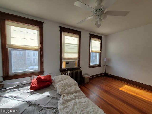 bedroom featuring ceiling fan, wood-type flooring, radiator, and cooling unit