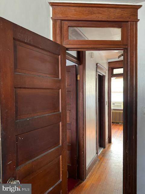 corridor with light wood-type flooring and radiator heating unit