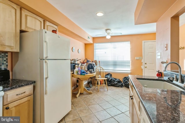 kitchen with sink, light brown cabinets, dark stone counters, and white refrigerator