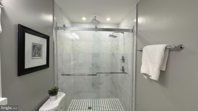 bathroom with a shower with door and toilet