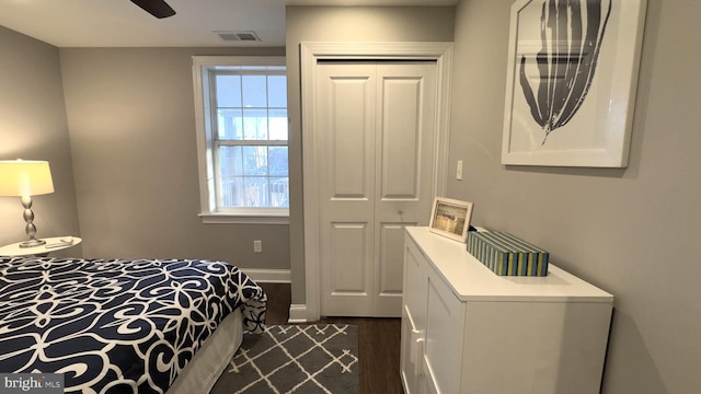 bedroom with ceiling fan, dark wood-type flooring, and a closet