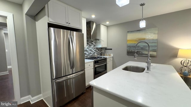 kitchen featuring appliances with stainless steel finishes, tasteful backsplash, wall chimney exhaust hood, sink, and white cabinetry