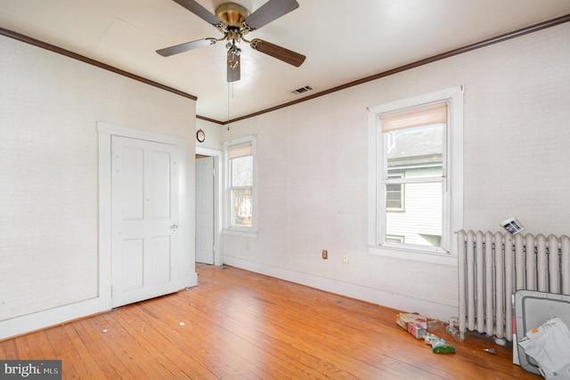 unfurnished bedroom featuring radiator, baseboards, visible vents, light wood finished floors, and crown molding