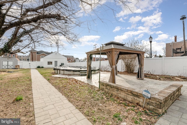 view of patio / terrace featuring a gazebo, a storage unit, a fenced backyard, and an outdoor structure