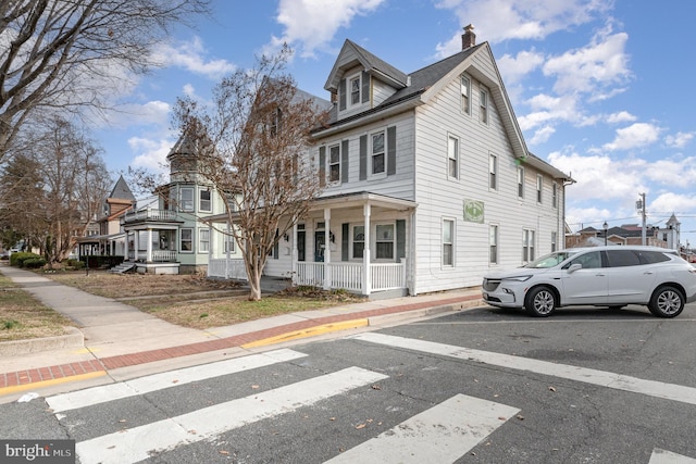 traditional style home featuring covered porch, a residential view, and a chimney