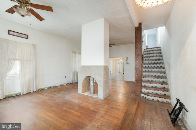 unfurnished living room featuring stairway, ceiling fan, and wood-type flooring