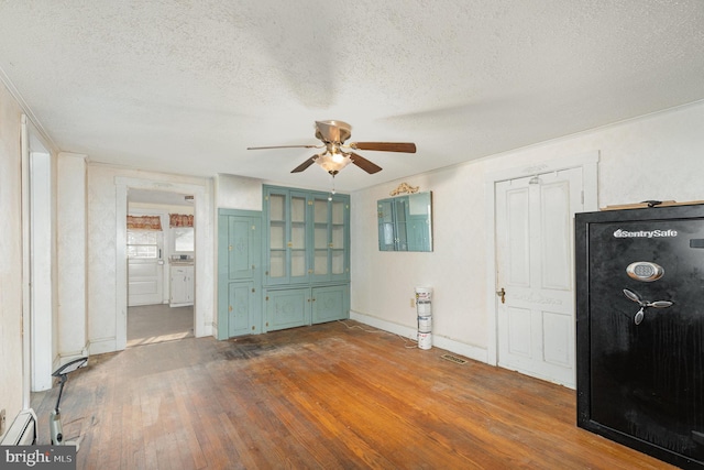 empty room with visible vents, a textured ceiling, hardwood / wood-style floors, baseboards, and ceiling fan