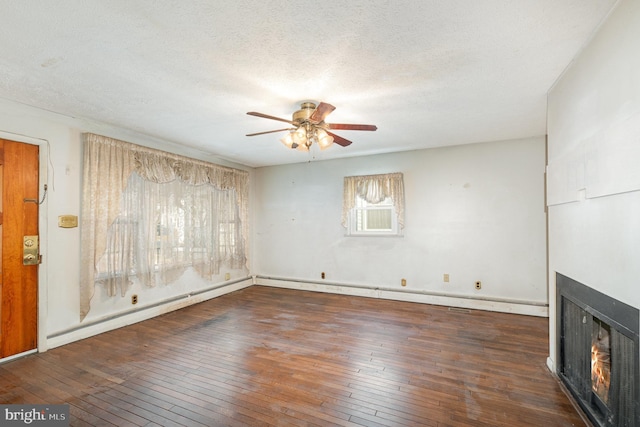 unfurnished living room with a ceiling fan, a textured ceiling, wood-type flooring, a lit fireplace, and baseboard heating