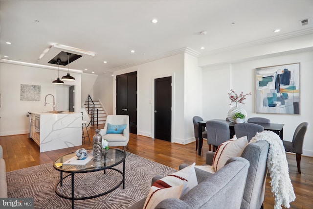 living room with hardwood / wood-style flooring, crown molding, and sink