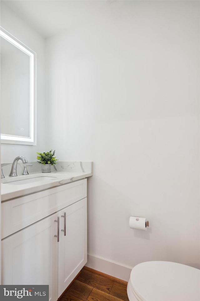 bathroom with hardwood / wood-style flooring, vanity, and toilet