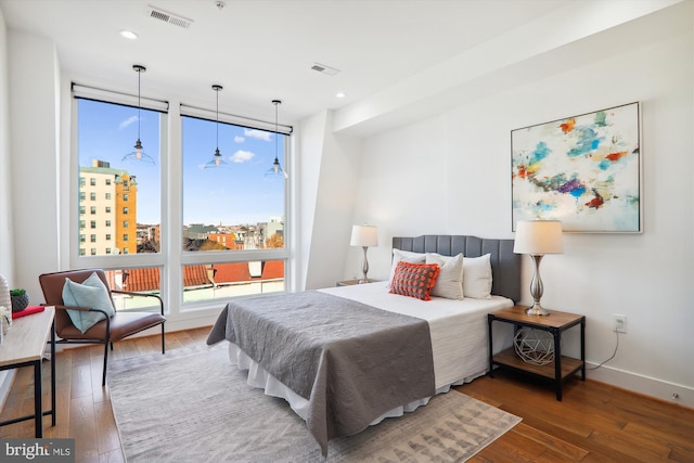 bedroom featuring expansive windows and dark hardwood / wood-style floors