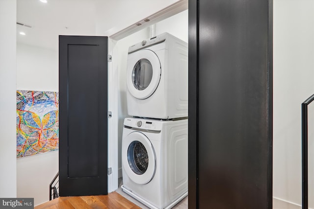 washroom featuring light hardwood / wood-style flooring and stacked washer and clothes dryer