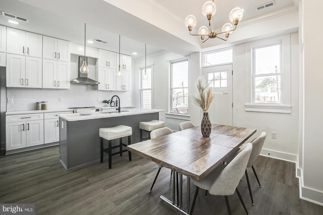 dining area with a healthy amount of sunlight, dark hardwood / wood-style flooring, sink, and an inviting chandelier