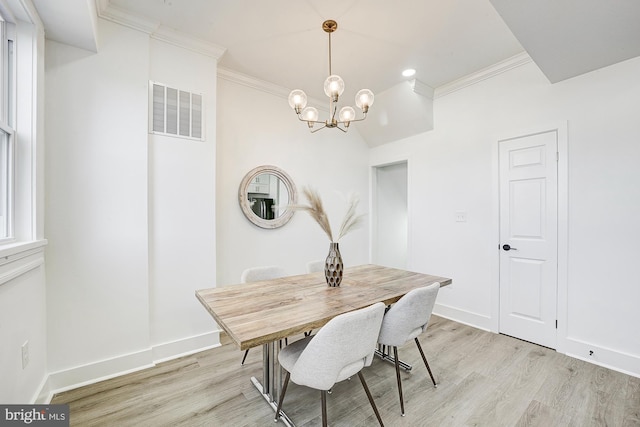 dining room with a chandelier, light wood-type flooring, and crown molding