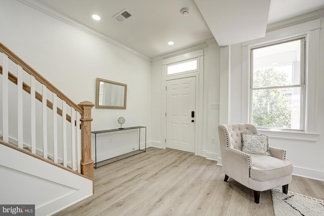 entryway with crown molding and light hardwood / wood-style flooring