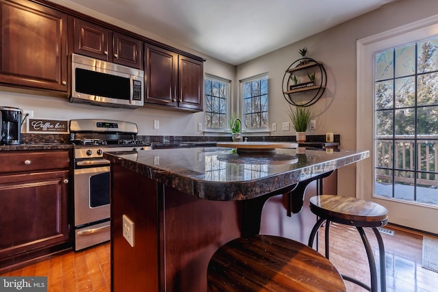 kitchen featuring appliances with stainless steel finishes, sink, light hardwood / wood-style flooring, a kitchen island, and a breakfast bar area