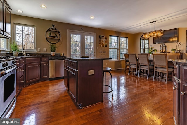 kitchen with a kitchen breakfast bar, stainless steel appliances, a healthy amount of sunlight, decorative light fixtures, and a kitchen island