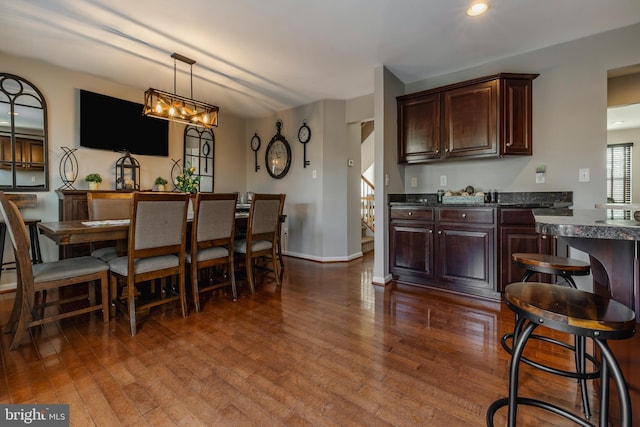 kitchen featuring dark hardwood / wood-style floors, dark brown cabinets, and decorative light fixtures