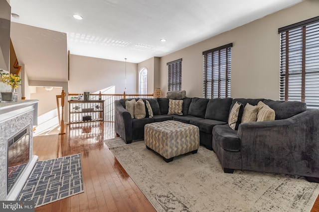 living room with hardwood / wood-style floors and a stone fireplace