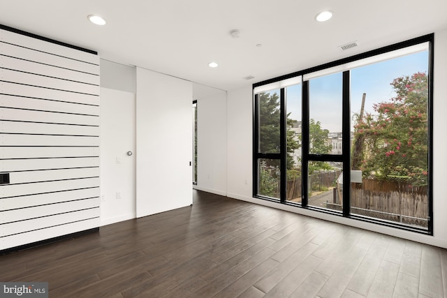 spare room with plenty of natural light, floor to ceiling windows, and dark wood-type flooring