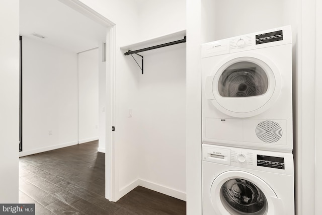 clothes washing area featuring stacked washer and dryer and dark wood-type flooring