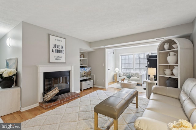 living room with built in shelves, a fireplace, and hardwood / wood-style flooring