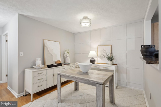 home office with a textured ceiling and light hardwood / wood-style flooring