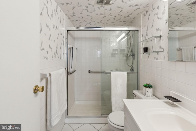 bathroom with tile patterned floors, toilet, tile walls, and walk in shower