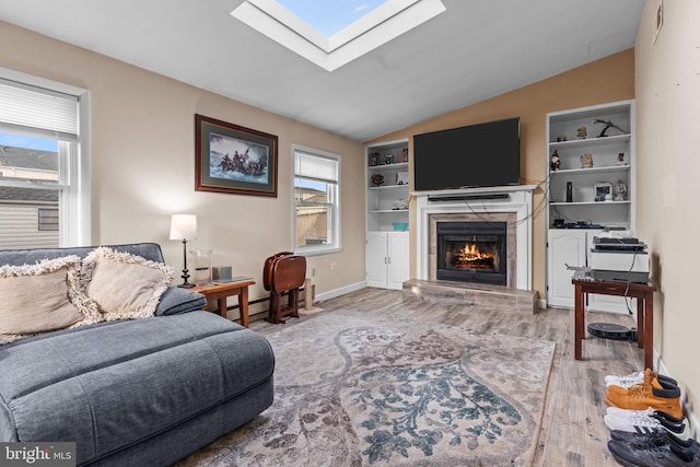 living room featuring light hardwood / wood-style flooring, lofted ceiling with skylight, a baseboard radiator, and built in shelves