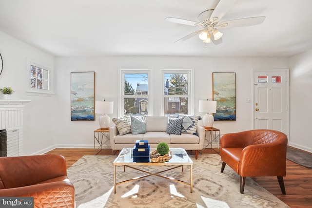 living room featuring ceiling fan, a fireplace, and wood-type flooring