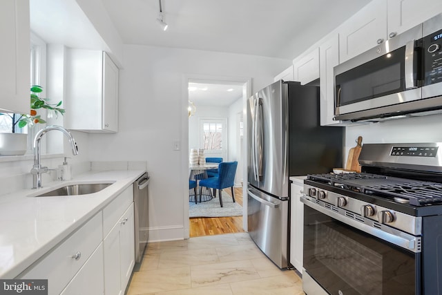 kitchen with light stone countertops, appliances with stainless steel finishes, white cabinetry, and sink