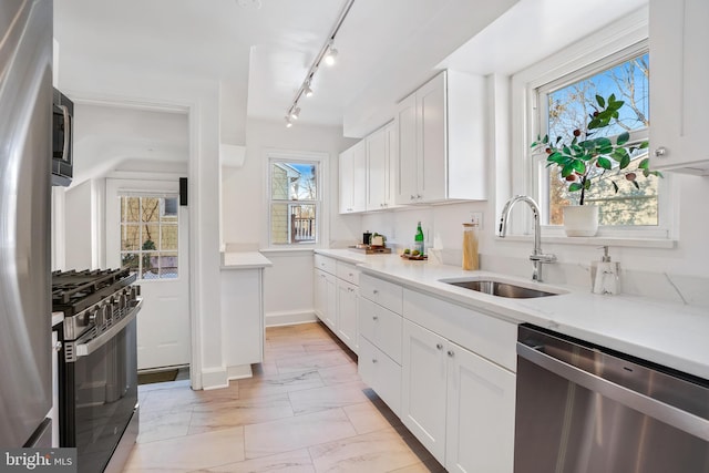 kitchen with a healthy amount of sunlight, white cabinetry, sink, and stainless steel appliances