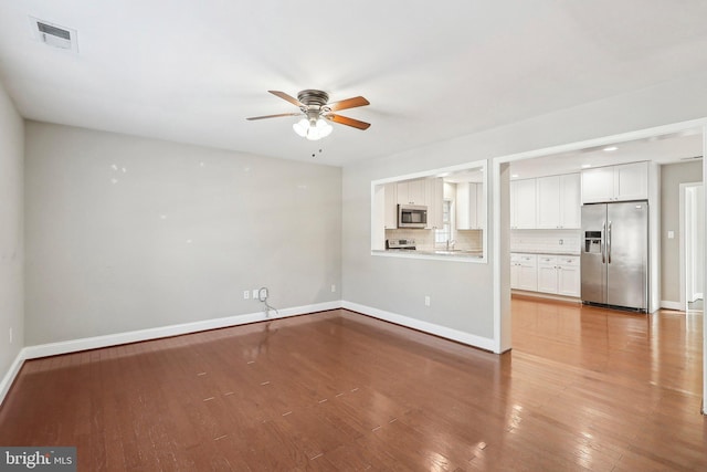 unfurnished living room featuring wood-type flooring, sink, and ceiling fan