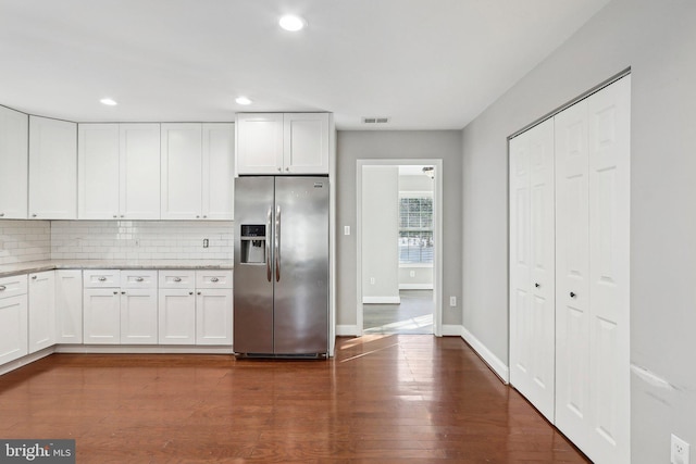 kitchen with stainless steel refrigerator with ice dispenser, dark hardwood / wood-style flooring, decorative backsplash, and white cabinets