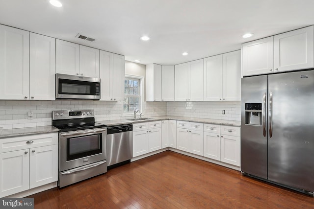 kitchen with appliances with stainless steel finishes, white cabinets, and light stone counters