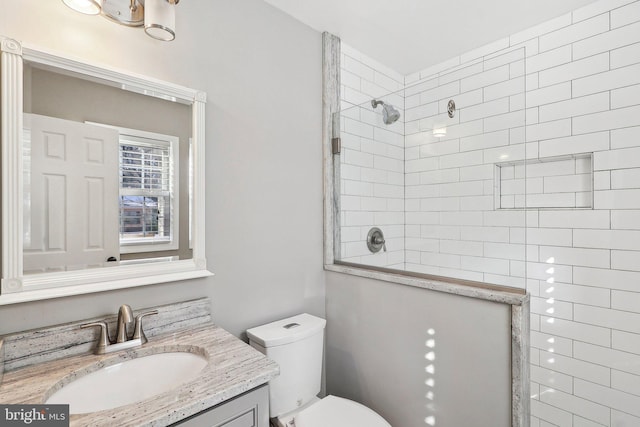 bathroom featuring vanity, toilet, and tiled shower