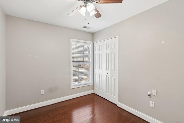 unfurnished bedroom featuring ceiling fan, dark hardwood / wood-style flooring, and a closet