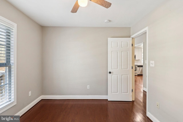 empty room featuring plenty of natural light, dark hardwood / wood-style floors, and ceiling fan