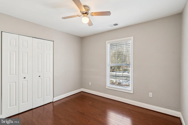 unfurnished bedroom featuring dark hardwood / wood-style floors, ceiling fan, and a closet