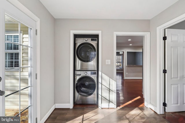 laundry room featuring dark hardwood / wood-style flooring and stacked washing maching and dryer