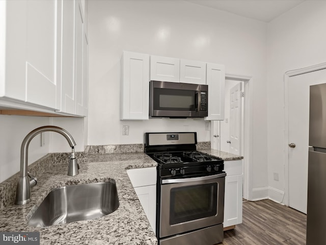 kitchen featuring light stone counters, stainless steel appliances, white cabinetry, and sink