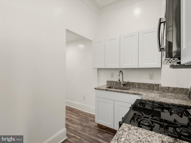 kitchen with black gas range, white cabinets, crown molding, sink, and light stone countertops