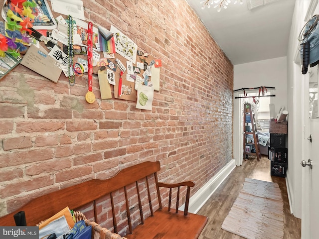 hallway with brick wall and wood-type flooring