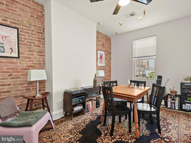 dining room featuring ceiling fan and brick wall