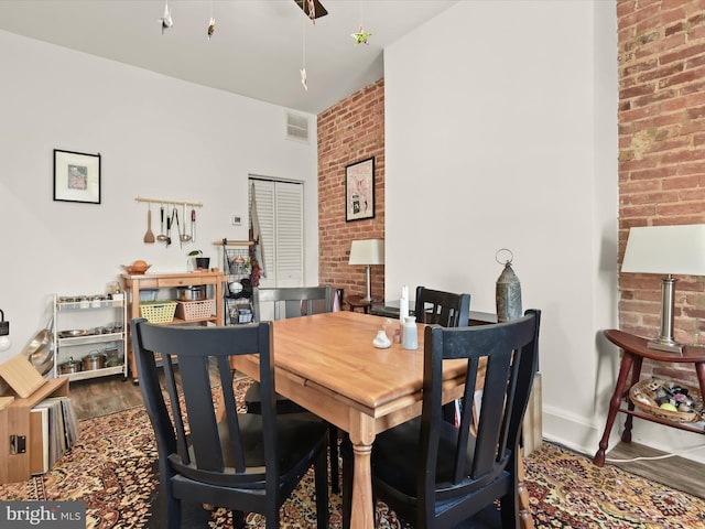 dining room featuring hardwood / wood-style flooring and brick wall