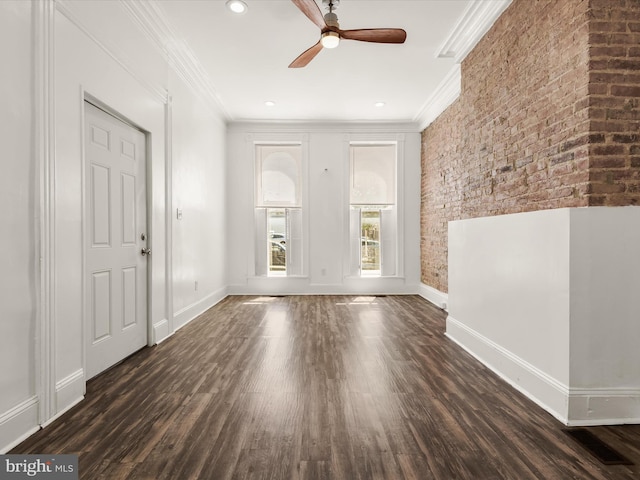 unfurnished room with ceiling fan, dark hardwood / wood-style flooring, crown molding, and brick wall