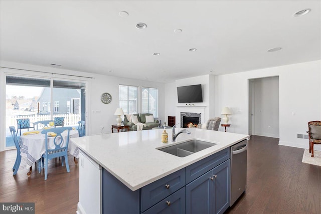 kitchen with stainless steel dishwasher, a center island with sink, dark hardwood / wood-style flooring, blue cabinets, and sink