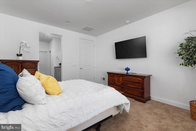 bedroom with light carpet and connected bathroom